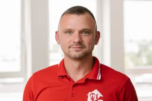 Porträt von Pascal. Pascal ist ein weißer Mann mit sehr kurz geschorenen braunen Haaren und er trägt ein rotes T-Shirt.